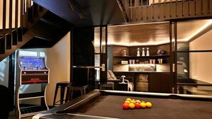 A pool table with balls, a Nintendo Wii console, and a bar area with stools and shelves. - Holiday Home in Kent with Hot Tub & Games Room (Appledore)