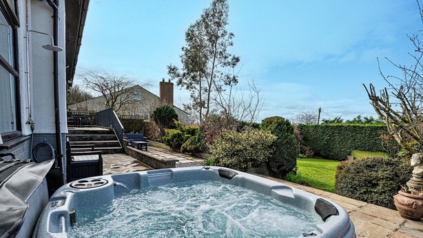 A hot tub in a backyard with a stone pathway leading to a house. - Bungalow in Dyserth with Hot Tub & Waterfall (Dyserth)