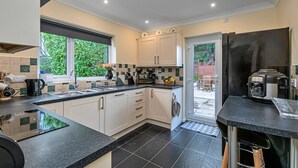 A modern kitchen with white cabinets, a black countertop, and a built-in oven. - Bungalow in Dyserth with Hot Tub & Waterfall (Dyserth)