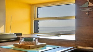 Una cocina con ventana que da a la playa, un fregadero y una encimera con una caja y una taza.