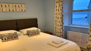 Una cama bien hecha con almohadas, una lámpara de noche y toallas.