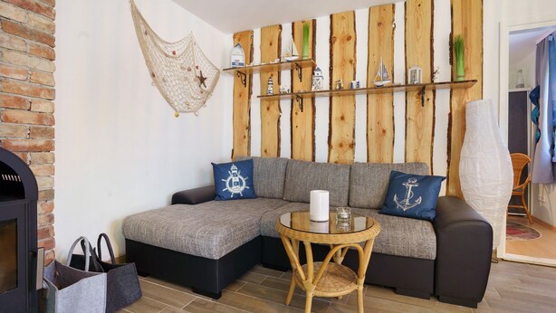 Ein gemütliches Wohnzimmer mit einer Eckcouch, einem kleinen runden Tisch, einem Kamin und Wanddekoration aus Holz.