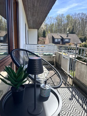 Un balcon avec une chaise, une petite table, une plante en pot et un objet décoratif.