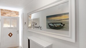 A hallway with a white door, a welcome sign, and a framed picture of a boat on water. - Holiday Apartment 'Traumhaft' with Shared Garden and Wi-Fi (Wasserburg)