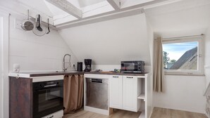 A compact kitchen with a built-in oven, dishwasher, and a microwave. - Holiday Apartment 'Traumhaft' with Shared Garden and Wi-Fi (Wasserburg)