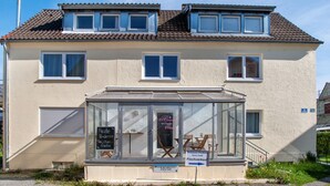 A two-story building with a ground-floor shop featuring a glass display and a sign indicating a restaurant and fish shop. - Holiday Apartment 'Traumhaft' with Shared Garden and Wi-Fi (Wasserburg)