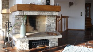 A stone fireplace with a wooden mantel, a vase, and a candle on top. - Holiday Home 'Talblick' with Mountain View, Private Terrace and Wi-Fi (Sasbachwalden)