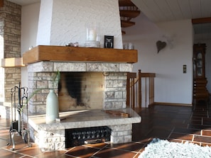 A stone fireplace with a wooden mantel, a vase, and a candle on top. - Holiday Home 'Talblick' with Mountain View, Private Terrace and Wi-Fi (Sasbachwalden)