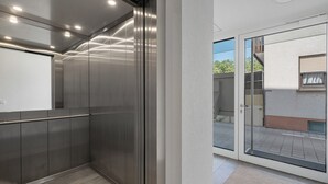 Un ascensor moderno con paredes metálicas y puerta de cristal que da a un espacio exterior.