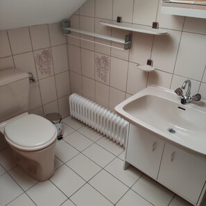 A bathroom with a toilet, sink, radiator, and tiled walls.