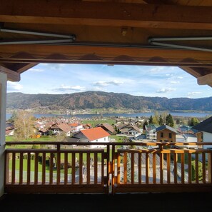 A balcony with a view of a lake, houses, and mountains.
