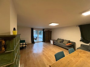 Amplia sala de estar con piso de madera, un sofá, una mesa de comedor y un ventanal corredero que da al exterior.