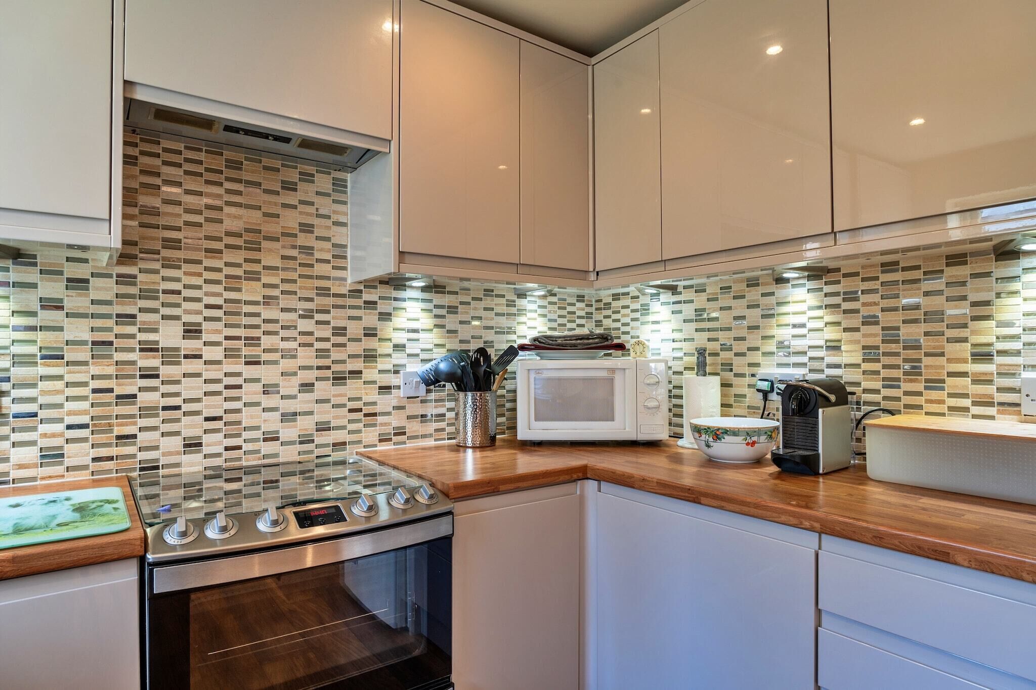 A modern kitchen with a tiled backsplash, stainless steel appliances, and wooden countertops.