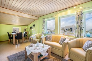 A cozy living room with a sofa, a coffee table, and a dining area with chairs and a table. - Apartment 'Fluss Aufwärts' with Private Terrace and Wi-Fi (Schülp)