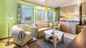 A cozy living room with a sofa, a coffee table, and a kitchen area with a wooden cabinet. - Apartment 'Fluss Aufwärts' with Private Terrace and Wi-Fi (Schülp)