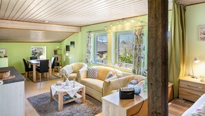 A cozy living room with a dining area, a sofa set, a coffee table, and a TV. - Apartment 'Fluss Aufwärts' with Private Terrace and Wi-Fi (Schülp)