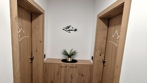 En hall med trädörrar, en liten växt på ett svart bord och en väggdekoration.