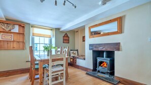 A cozy room with a wooden dining table, chairs, a fireplace, and a window with blinds.