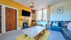 A living room with a wooden coffee table, a blue sofa, a fireplace, and a television mounted on the wall.