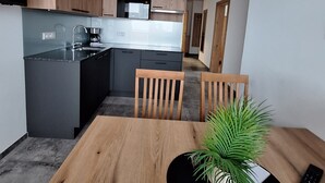 A modern kitchen with dark cabinetry, a built-in microwave, and a coffee maker. - Apartment '1' with Mountain View, Shared Garden and Wi-Fi (Sonnenalpe Nassfeld)