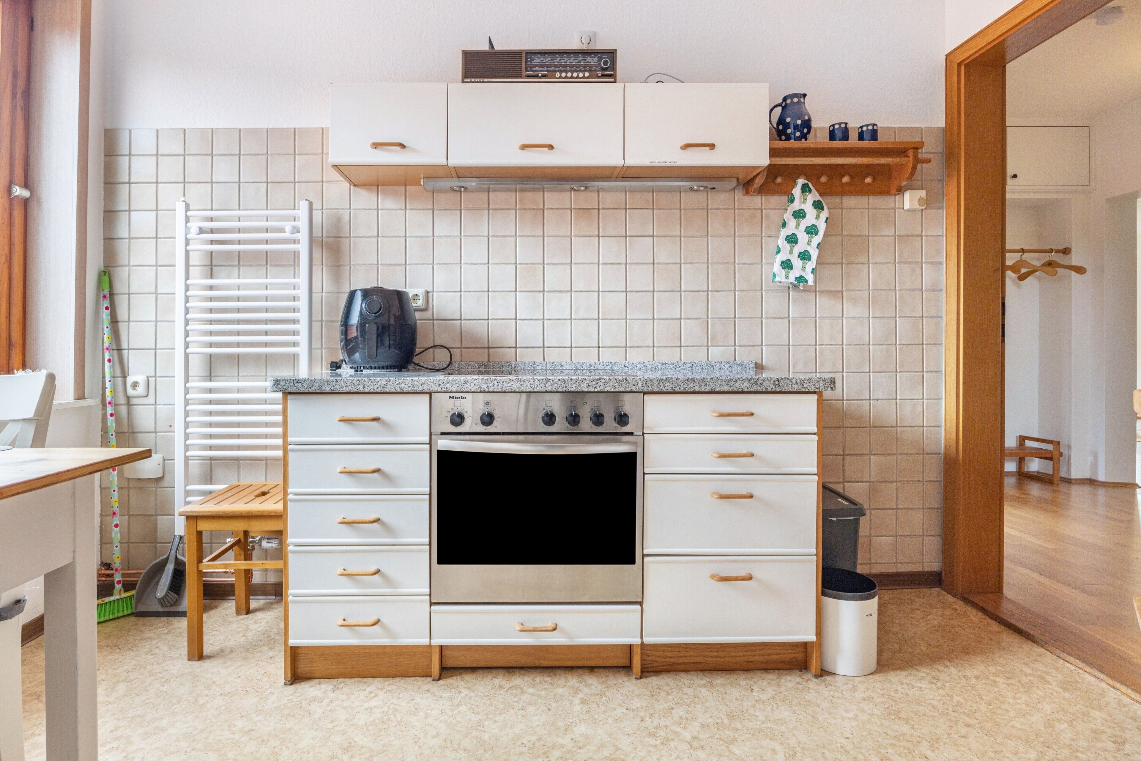 A kitchen with white cabinets, a built-in oven, a coffee maker, and a tiled backsplash.