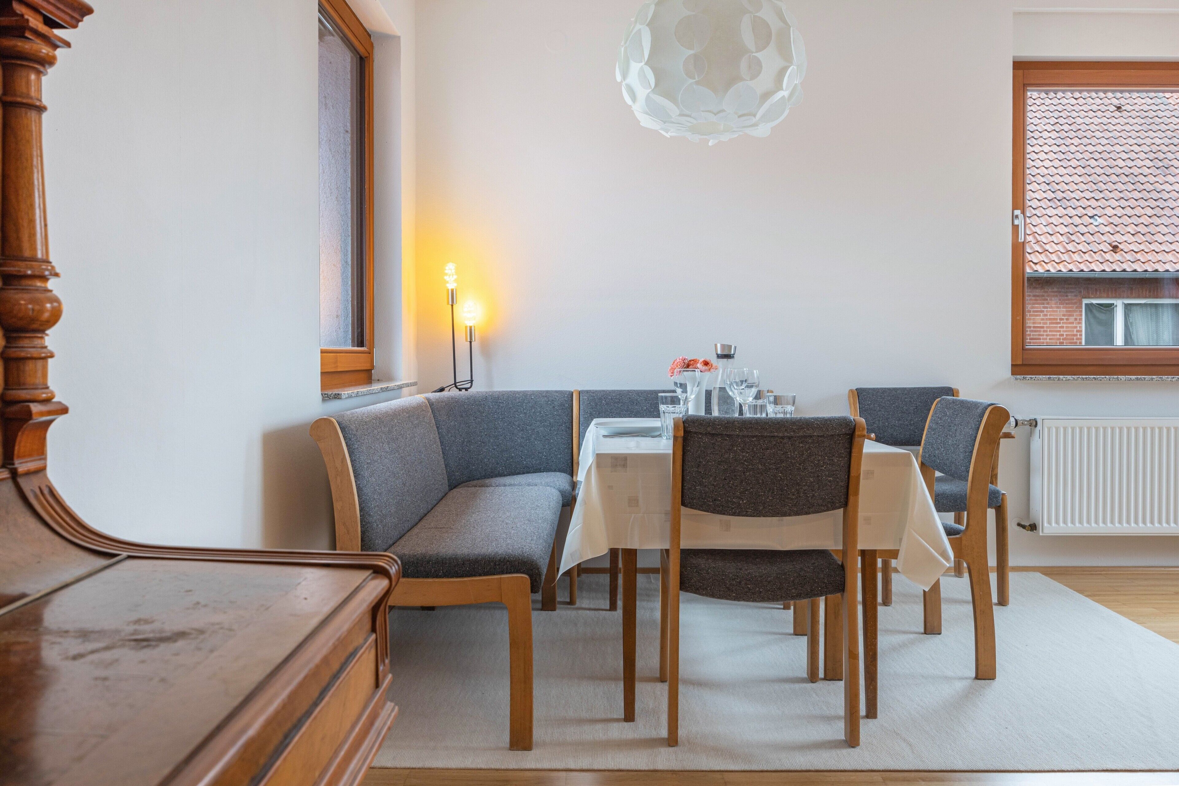 Ein Essbereich mit Tisch, Stühlen, einer Bank, einer Lampe und einem Fenster mit Ausblick.