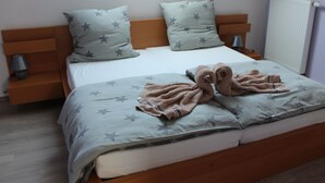 Une chambre à coucher avec un lit, des oreillers à motifs étoilés, une table de chevet avec une lampe et un radiateur.