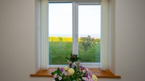 Ein Zimmer mit einem großen Fenster, einem hölzernen Vorsprung und einer Vase mit Blumen.