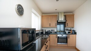 Eine moderne Küche mit Edelstahlgeräten, Holzschränken und einem eingebauten Backofen.