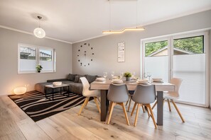 Un espace repas moderne avec une table en bois, des chaises grises et un tapis à motifs zébrés.