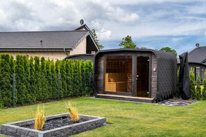 Une maison moderne à l’extérieur aux lignes courbes originales, avec un intérieur où le bois est apparent et un jardin bien entretenu.