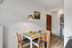 Un petit coin repas comprenant une table, des chaises, une lampe suspendue, un tableau et une porte en bois.