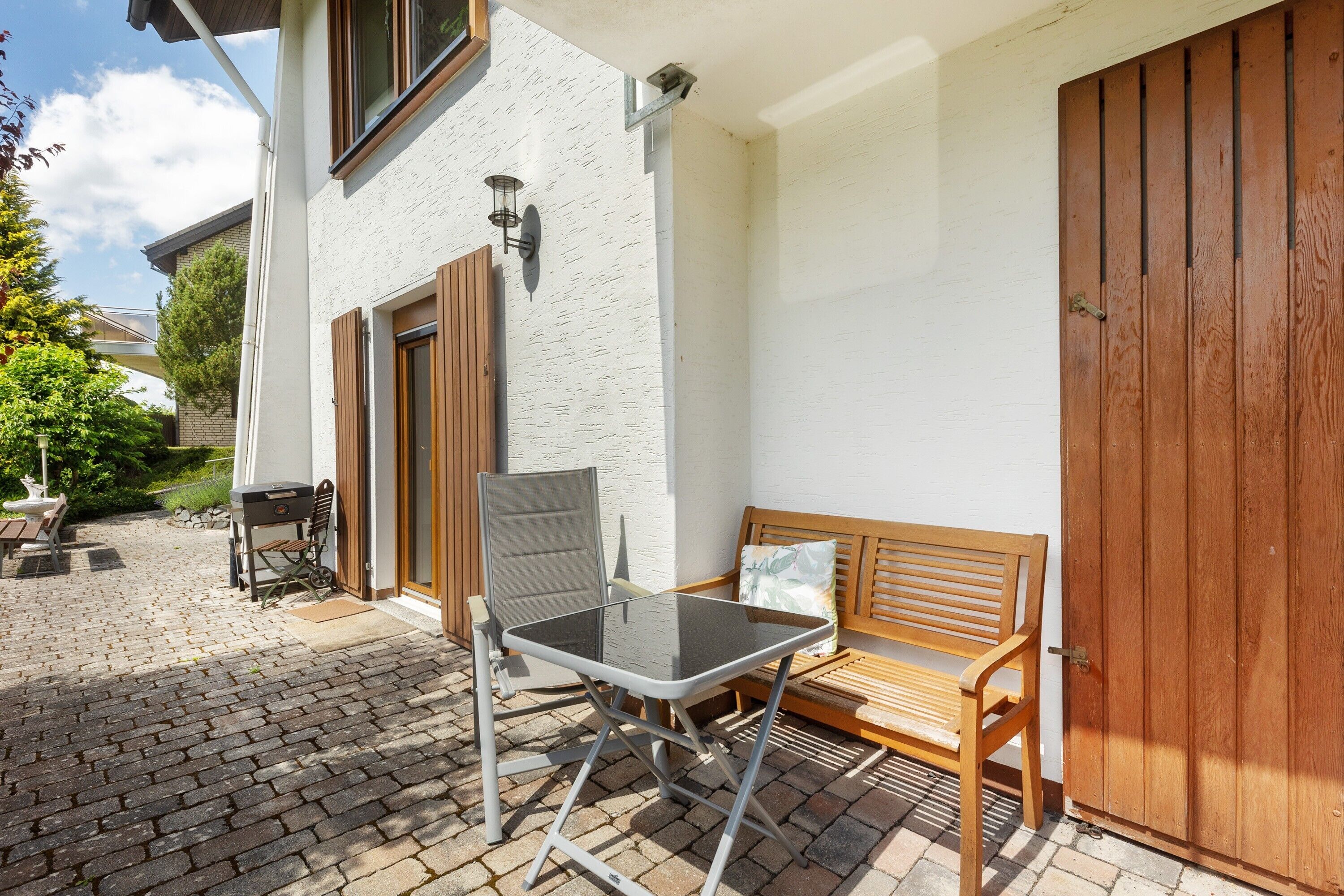 A patio with a table and chairs, a wooden bench, and a large wooden door.