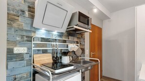 A compact kitchenette with a microwave, kettle, and sink.