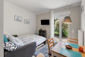 Une chambre moderne équipée d’un lit, d’une télévision, d’une table à manger et offrant une vue sur l’extérieur.