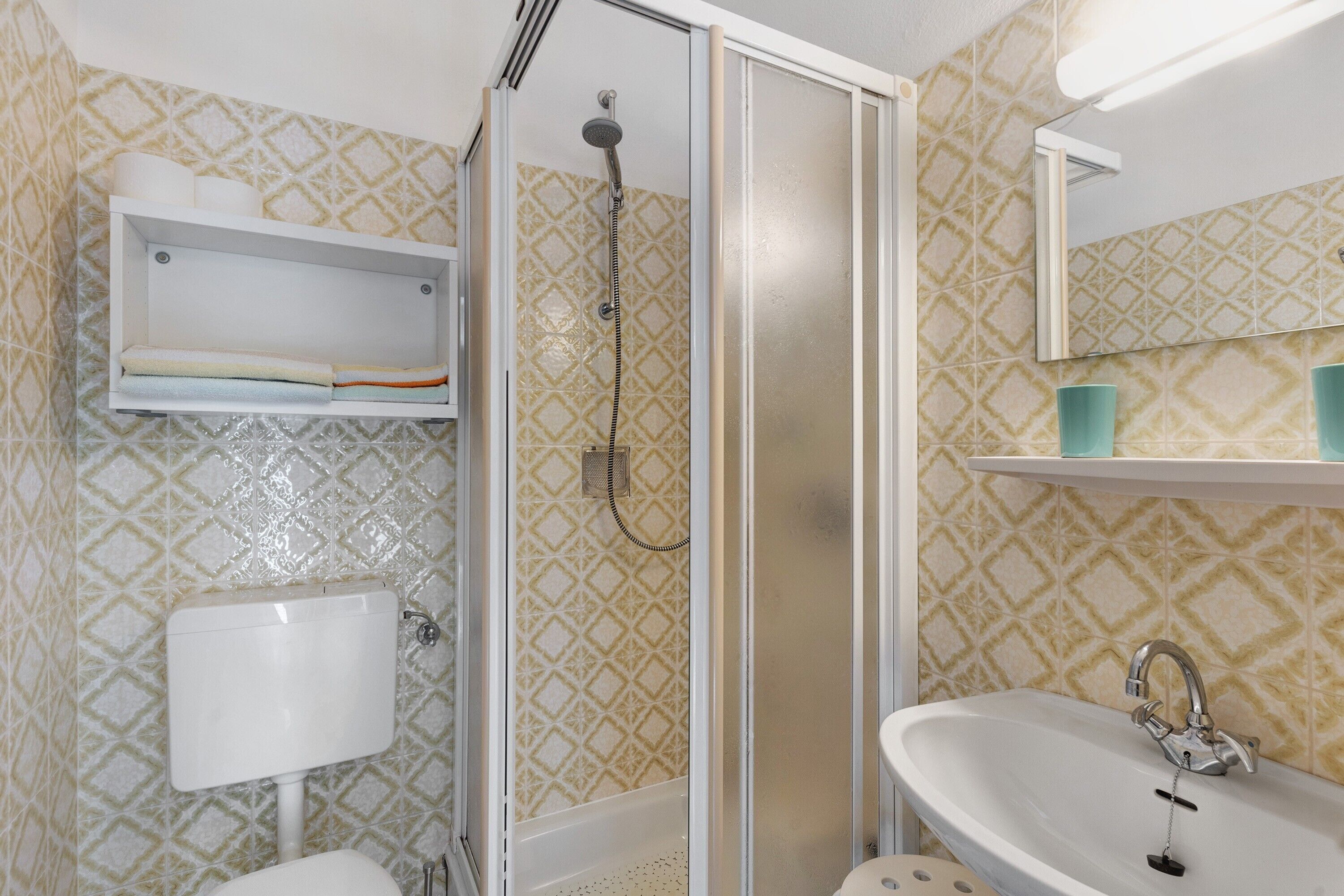 A bathroom with a shower, toilet, sink, and a mirror.