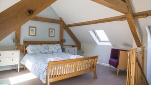 Une chambre à coucher avec un lit en bois, une table de chevet, une chaise et une lucarne.