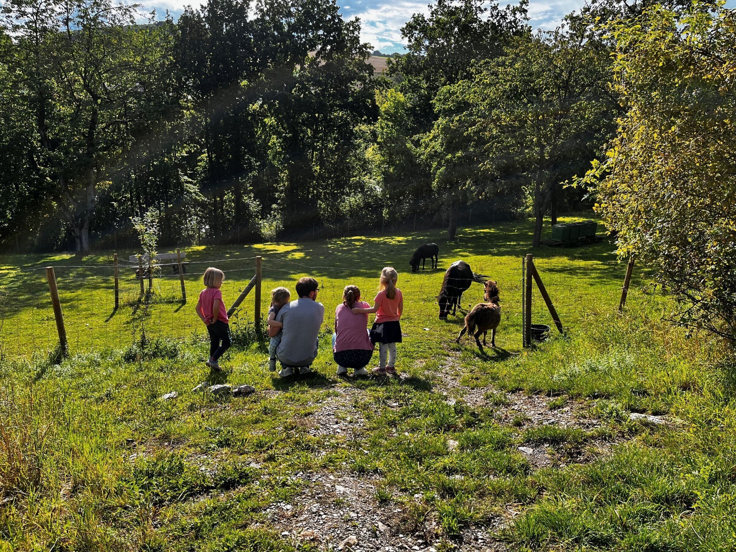Een groep mensen staat in een grasveld, met bomen op de achtergrond.