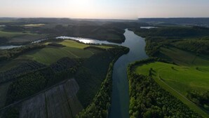 Een luchtbeeld van een rivier die zich kronkelend door groene velden en beboste gebieden slingert.