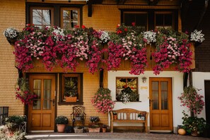 A building with a wooden door, a bench, and potted plants. - Apartment 'Im Heustock, 130qm' with Shared Terrace, Shared Garden and Wi-Fi (Titisee-Neustadt)