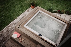 Ein Whirlpool auf einer Holterrasse mit einem Blumentopf und einem Buch.