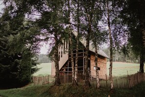 Una rustica baita di legno circondata da alberi in un ambiente rurale.