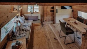 Una cabaña acogedora con un dormitorio en el altillo, un comedor y una sala de estar.