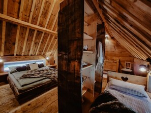 Una baita in legno con camera soppalcata, arredata con un letto, una scrivania e una sedia.