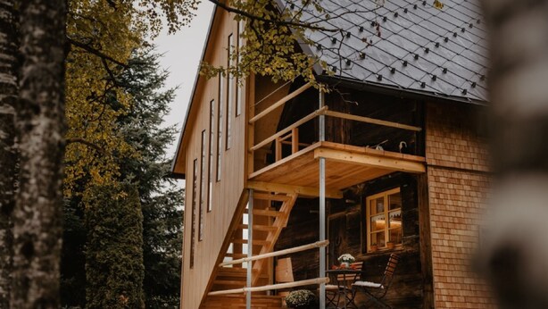 Una cabaña de madera con un balcón, una escalera y una ventana.