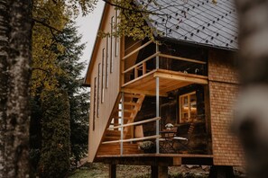 Une cabane en bois dotée d’un balcon, d’un escalier et d’une fenêtre.