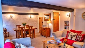 A cozy living room with a dining area, wooden furniture, a fireplace, and a bookshelf. - Cottage in Alcombe near Exmoor Park (Alcombe)