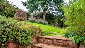 A stone staircase leading up to a garden area with a wooden gazebo and a large tree in the background. - Cottage in Alcombe near Exmoor Park (Alcombe)