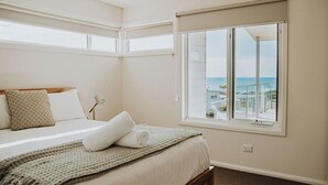 A bedroom with a bed, a window with a view of the sea, and a balcony.