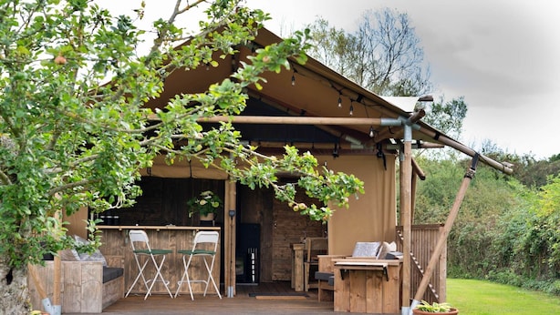 Une cabane en bois dotée d’une terrasse, d’un espace salon extérieur et d’un intérieur rustique.